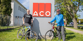 Zaměstnanci na kole před ACO značkou